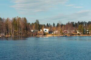 Waterfront homes and cottages along a calm lake in the Laurentians under a clear blue sky.