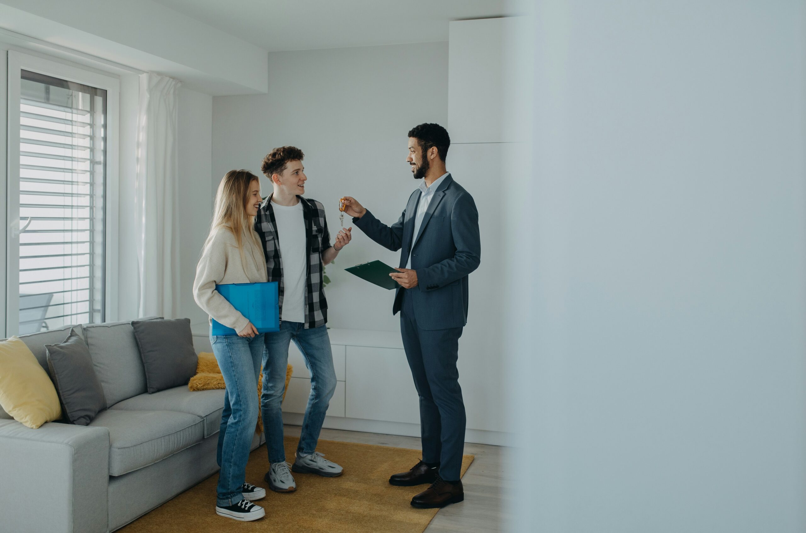 Broker handing over keys to a couple after acceptance of their offer to purchase