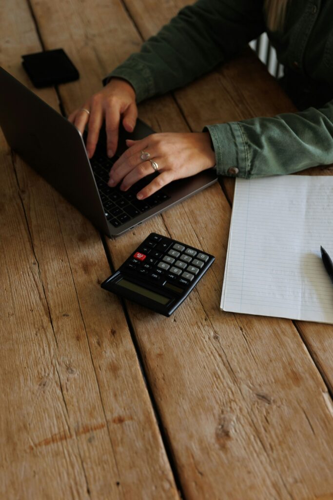 Calculating closing costs of a purchase with a calculator and laptop