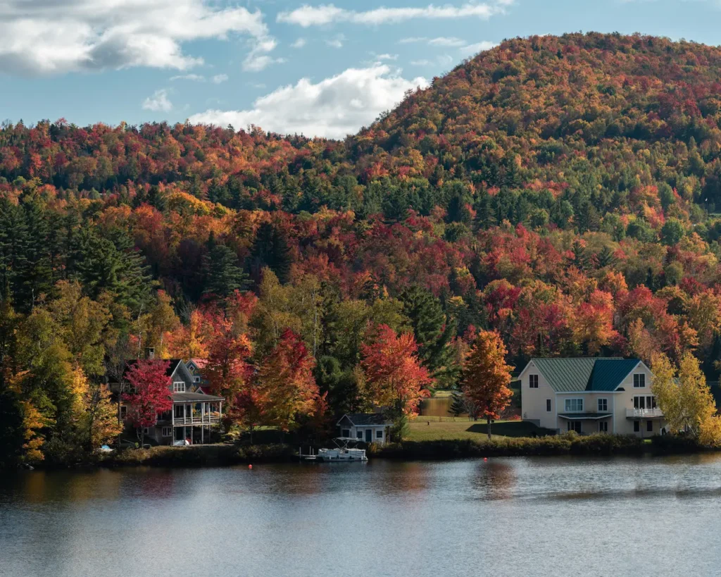 Cottage for sale in the Laurentians, by a lake surrounded by forest in the late afternoon